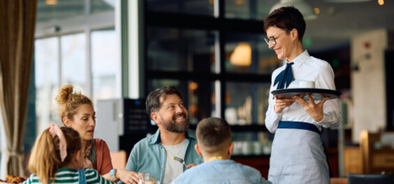 Cameriere che serve dei clienti al tavolo di un locale