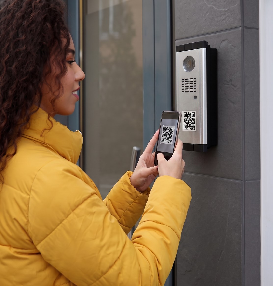 Una donna inquadra col telefono il QR OmnyQR sul citofono di un portone
